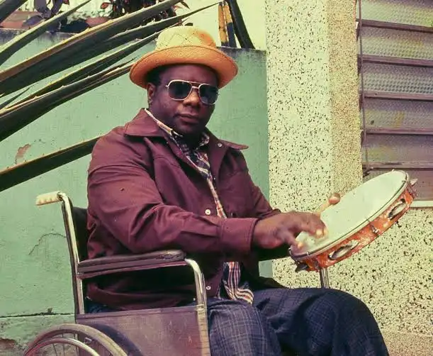 Candeia compositor de Preciso Me Encontrar tocando pandeiro em cadeira de rodas