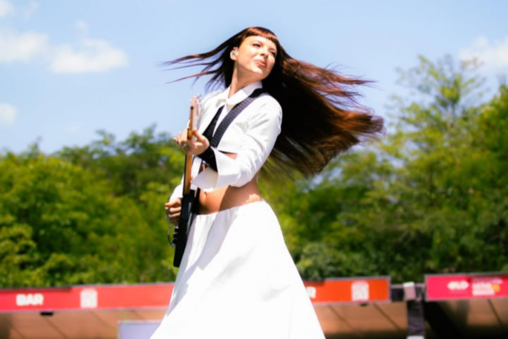 Júlia Mestre girando com sua guitarra no palco em festival de música