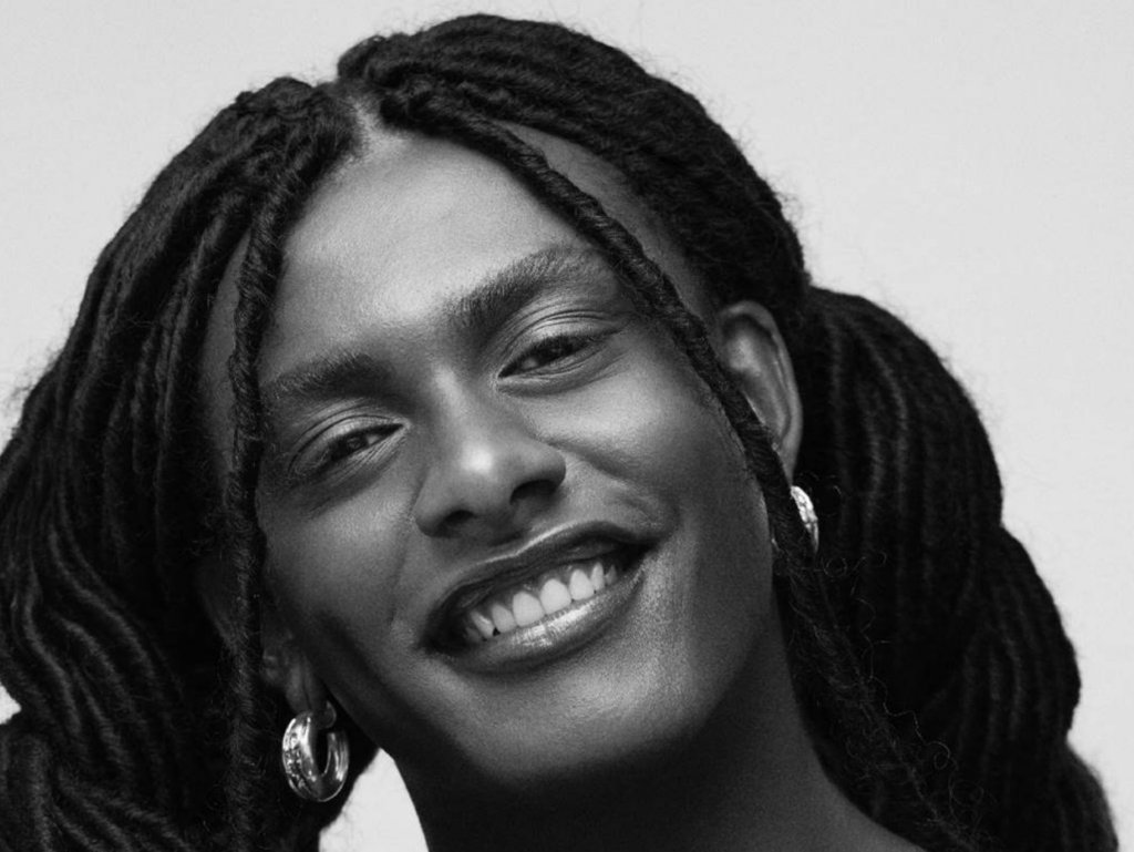 Rosto de Liniker sorrindo com cabelos trançados em preto e branco